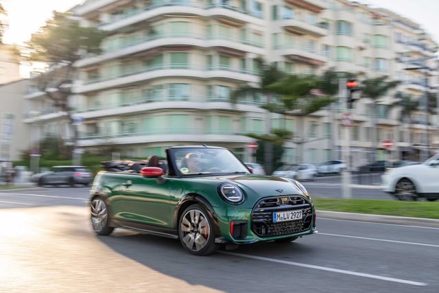 Le MINI John Cooper Works Convertible Sunny Side Yellow roule capote ouverte en vue trois-quarts avant sur route ensoleillée