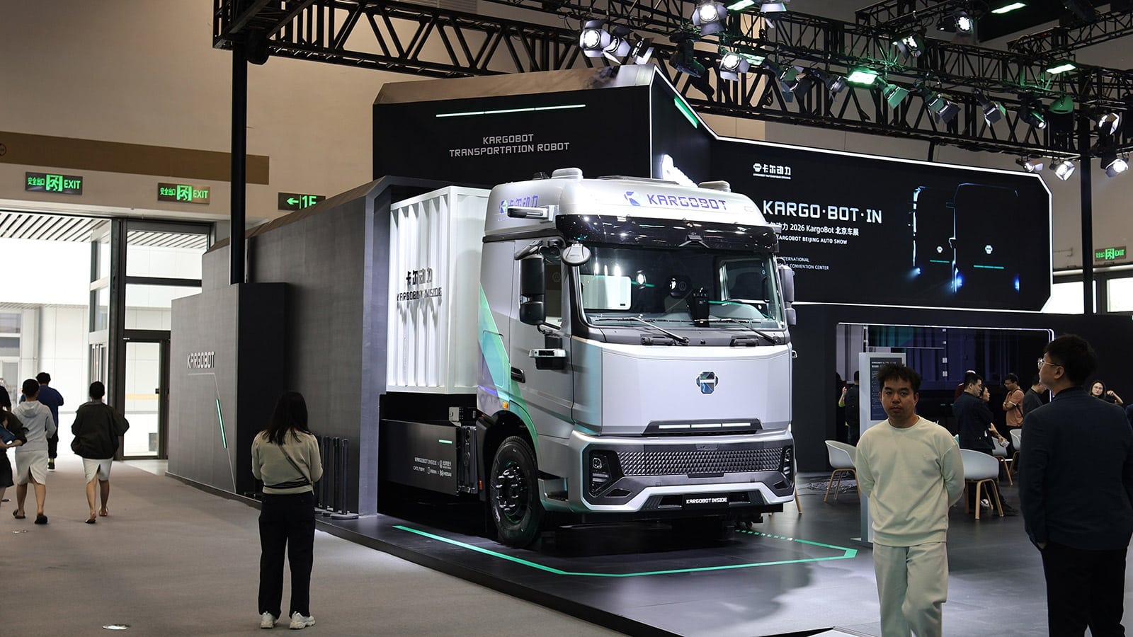 Un camion électrique blanc est branché en dépôt, avec des tracteurs routiers alignés derrière