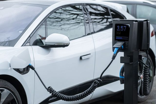 Citadines électriques abordables alignées en ville, Leapmotor T03 au premier plan et borne de recharge en arrière-plan